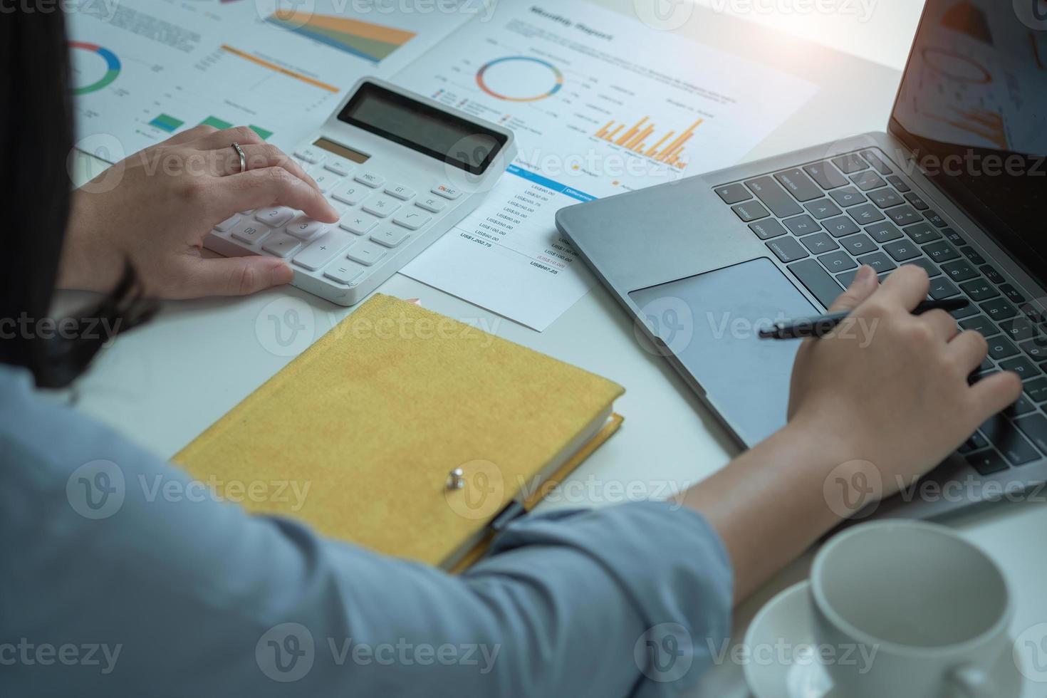 Portrait of a female accountant using a calculator and laptop to calculate balance using graphs for customers. photo