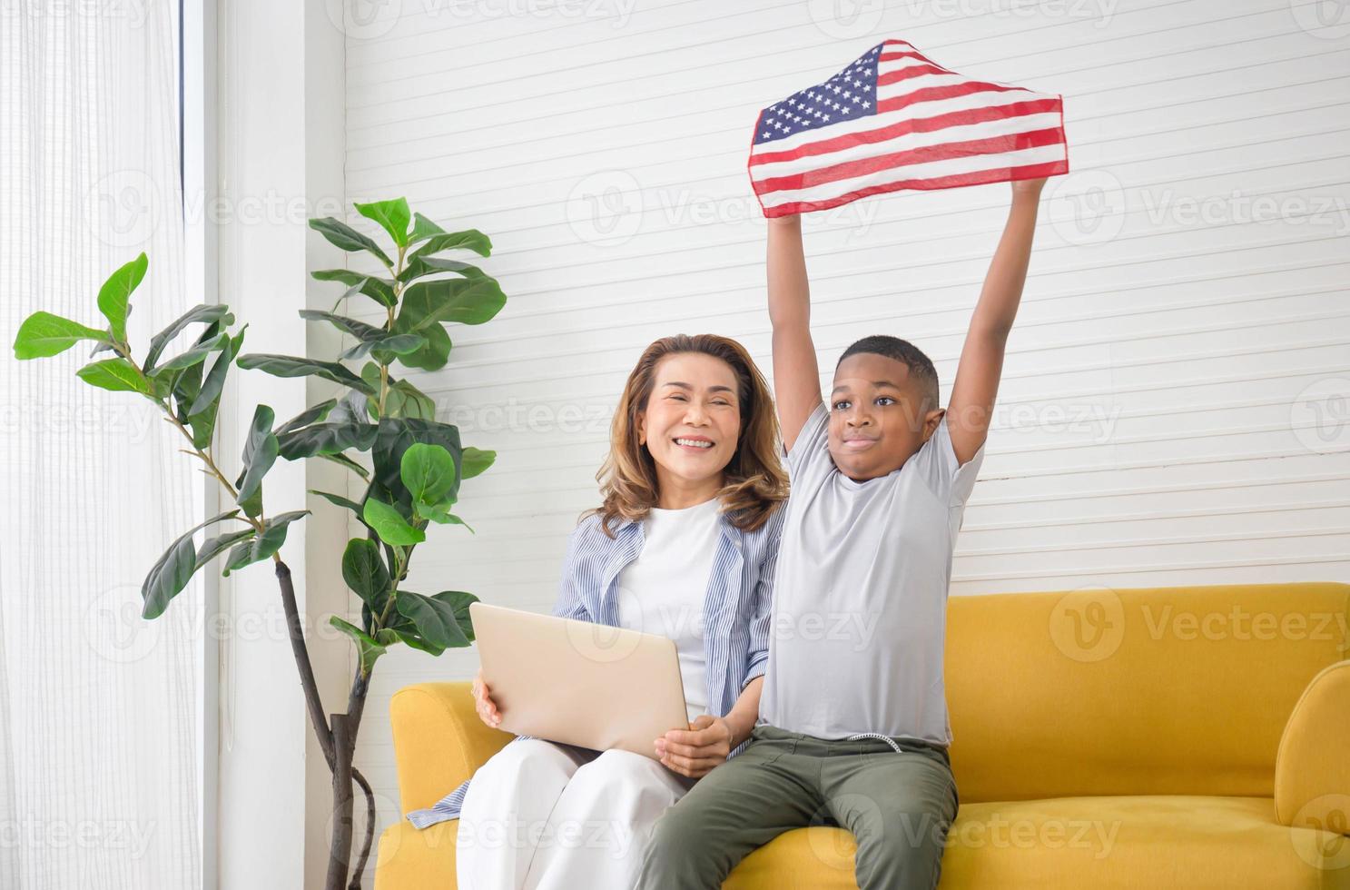 Children and grandmother playing cheerfully in living room, Woman with laptop and kid boy holding USA flag photo