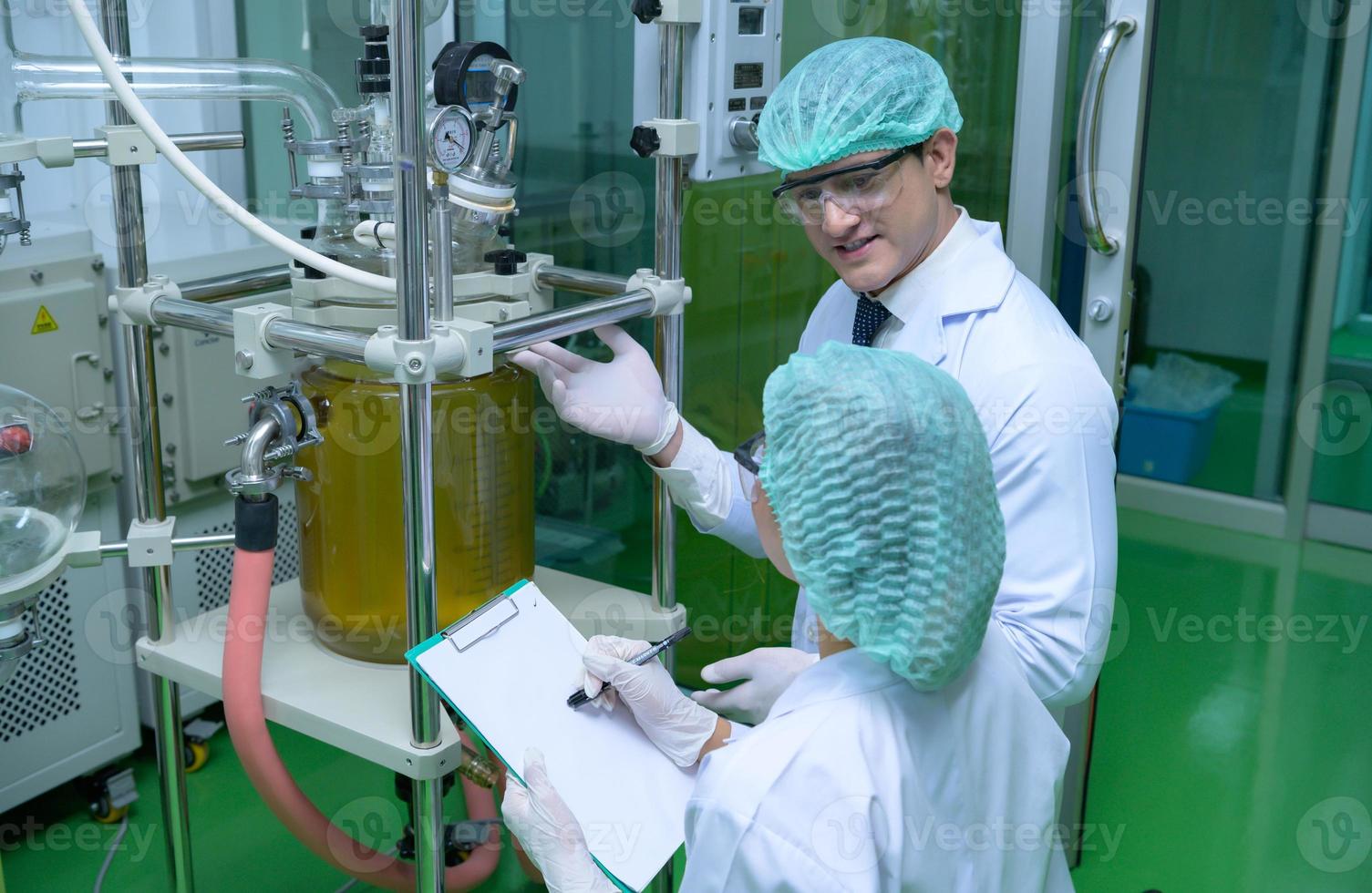 Scientists and assistants are in the machine room extracting oil and cannabis seeds. Inspecting cannabis oil extractor before starting to extract the prepared cannabis photo