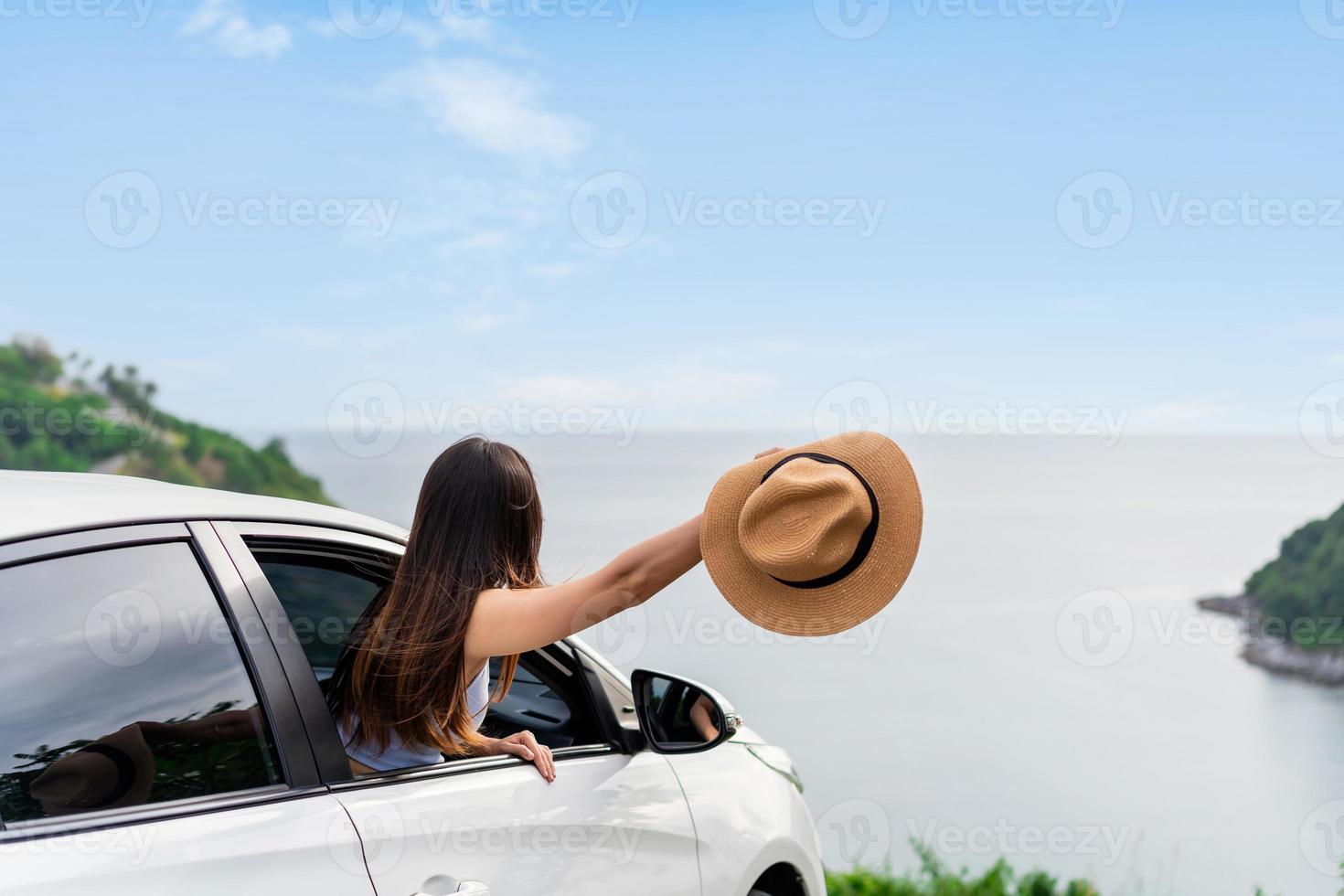 Young woman traveler looking at the beautiful sea view with her car while travel driving road trip on vacation photo