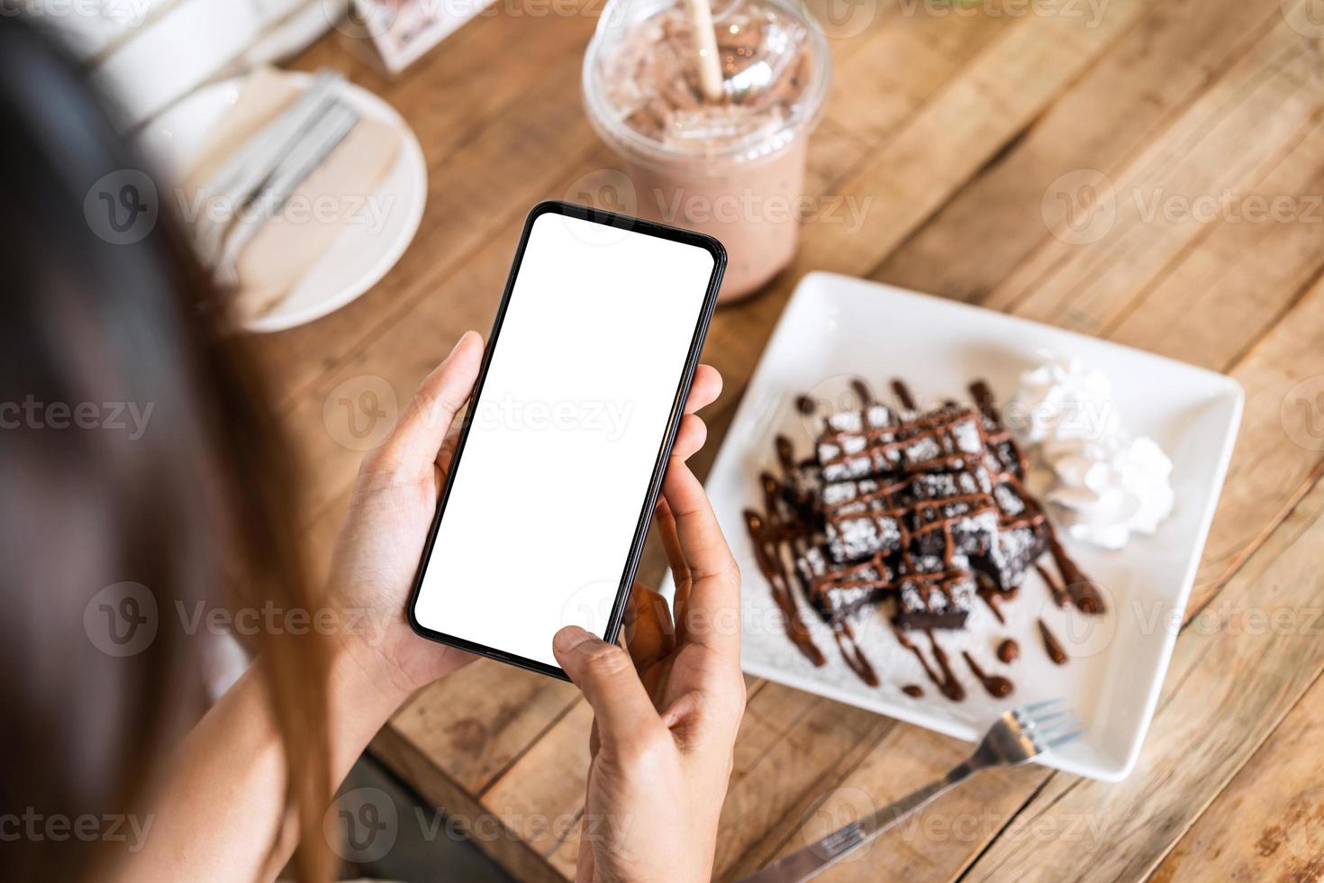 Young woman traveler using smart phone in cafe while traveling photo