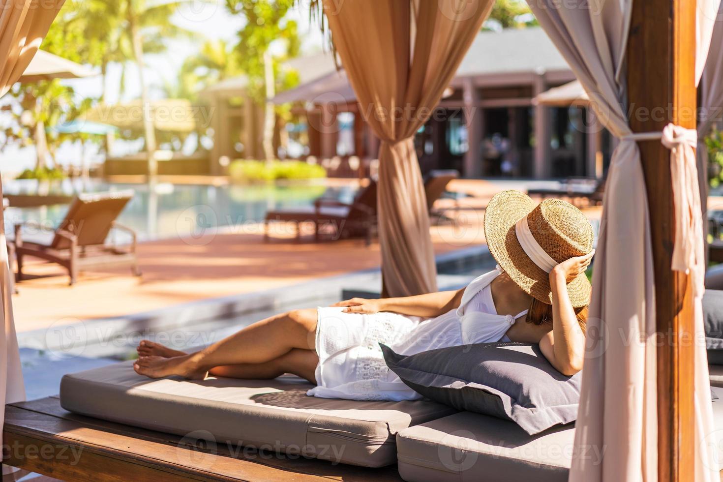 Young woman traveler relaxing and enjoying by a tropical resort pool while traveling for summer vacation photo