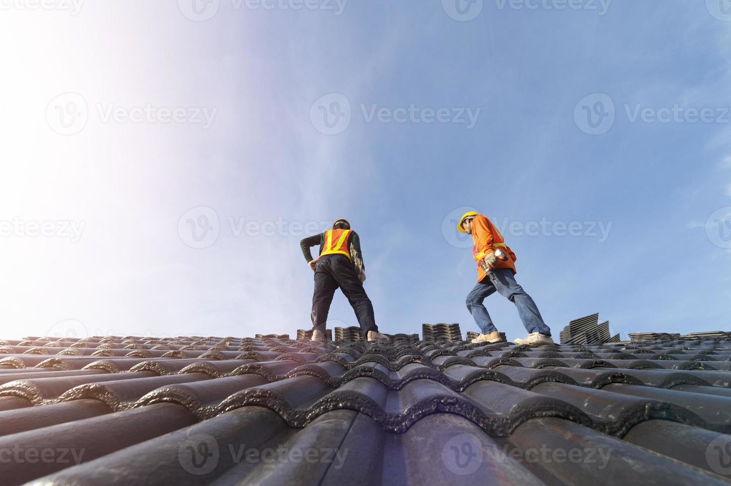 A team of construction workers in work clothes installed new roofing equipment. roofing tools, electric drill, and use it on new wood roofs with metal sheets. photo