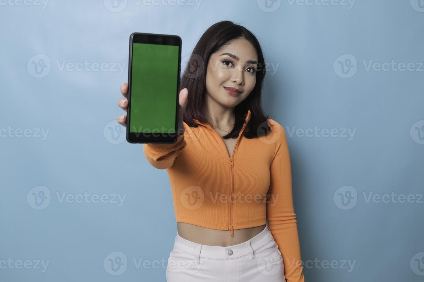 An excited young woman showing copy space on her smartphone in her hand, isolated on blue background photo
