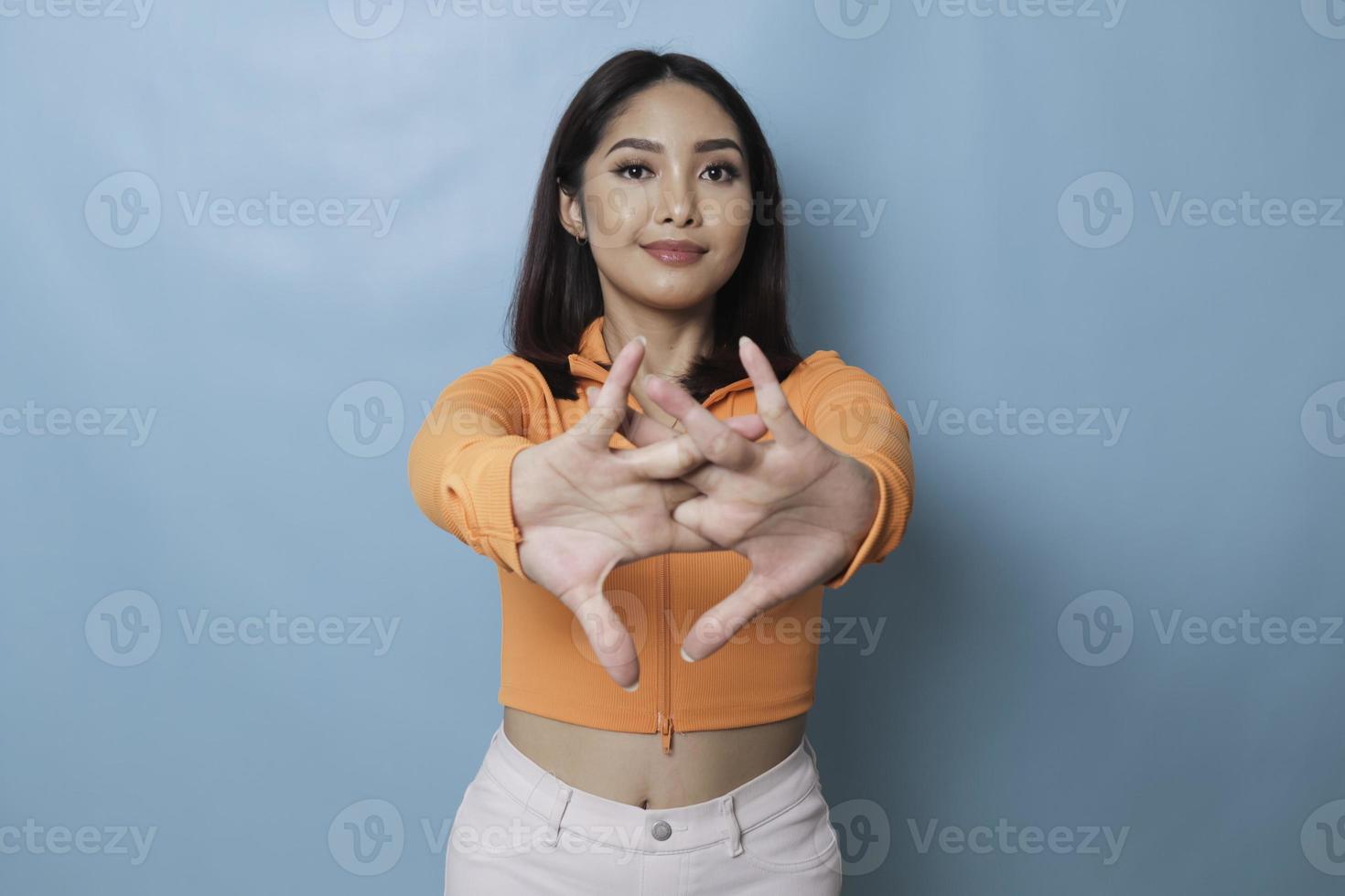 A portrait of a young Asian woman stretching her arms. Female doing warmup stretching workout on blue background. photo