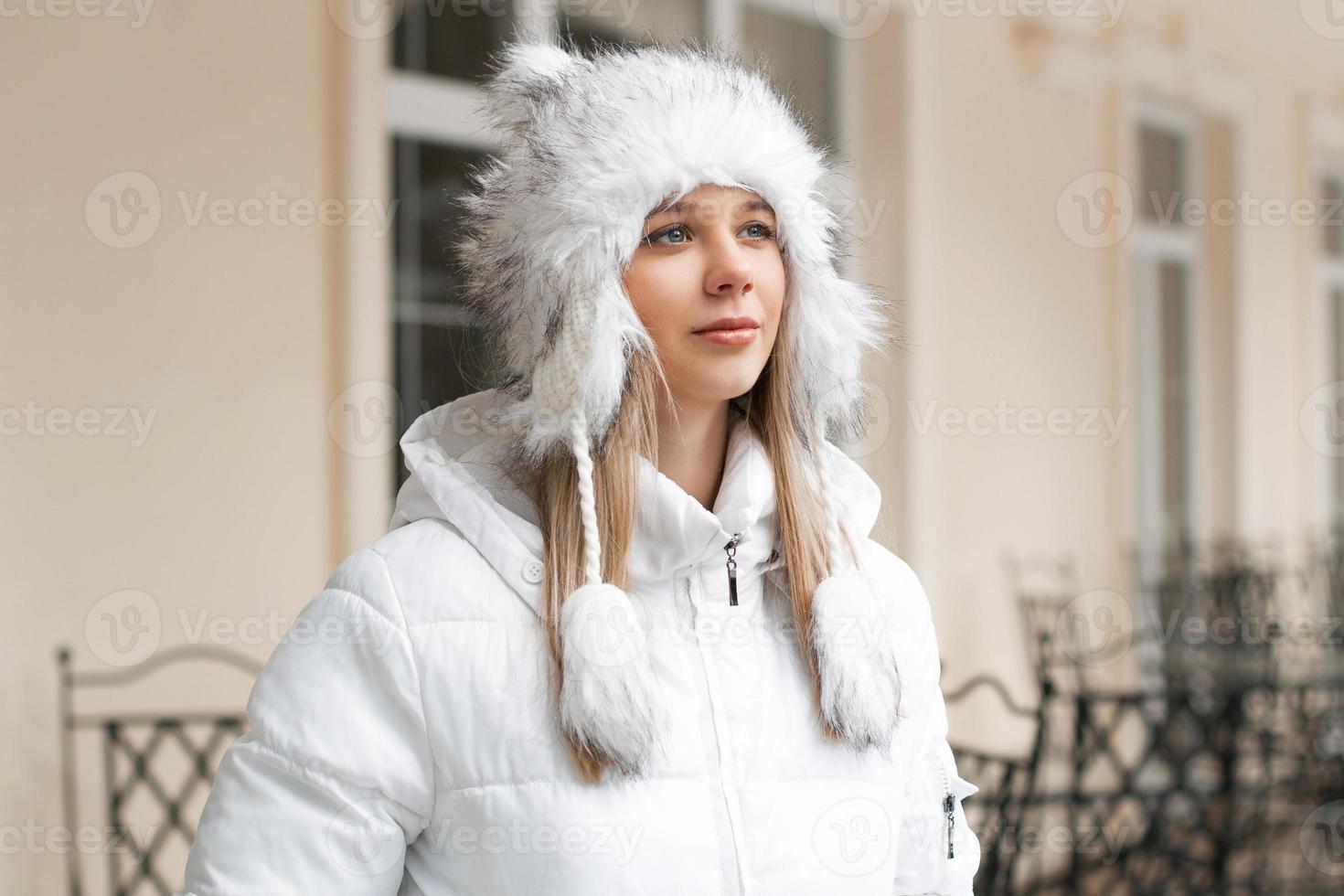 Beautiful woman in the winter jacket looking up near the building photo