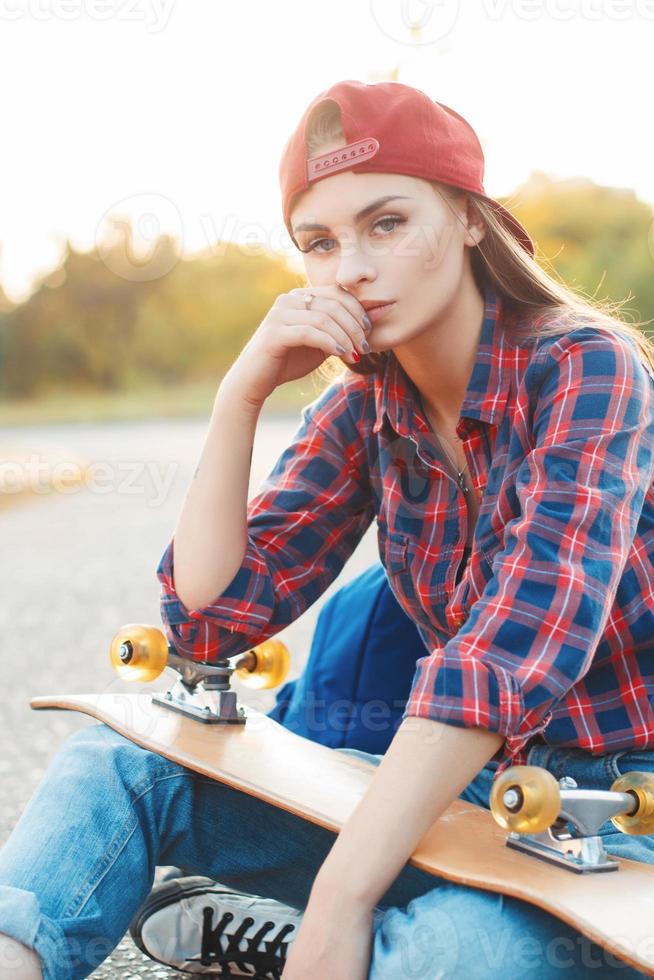 Fashion lifestyle, Beautiful young woman with skateboard, backlit at sunset. photo