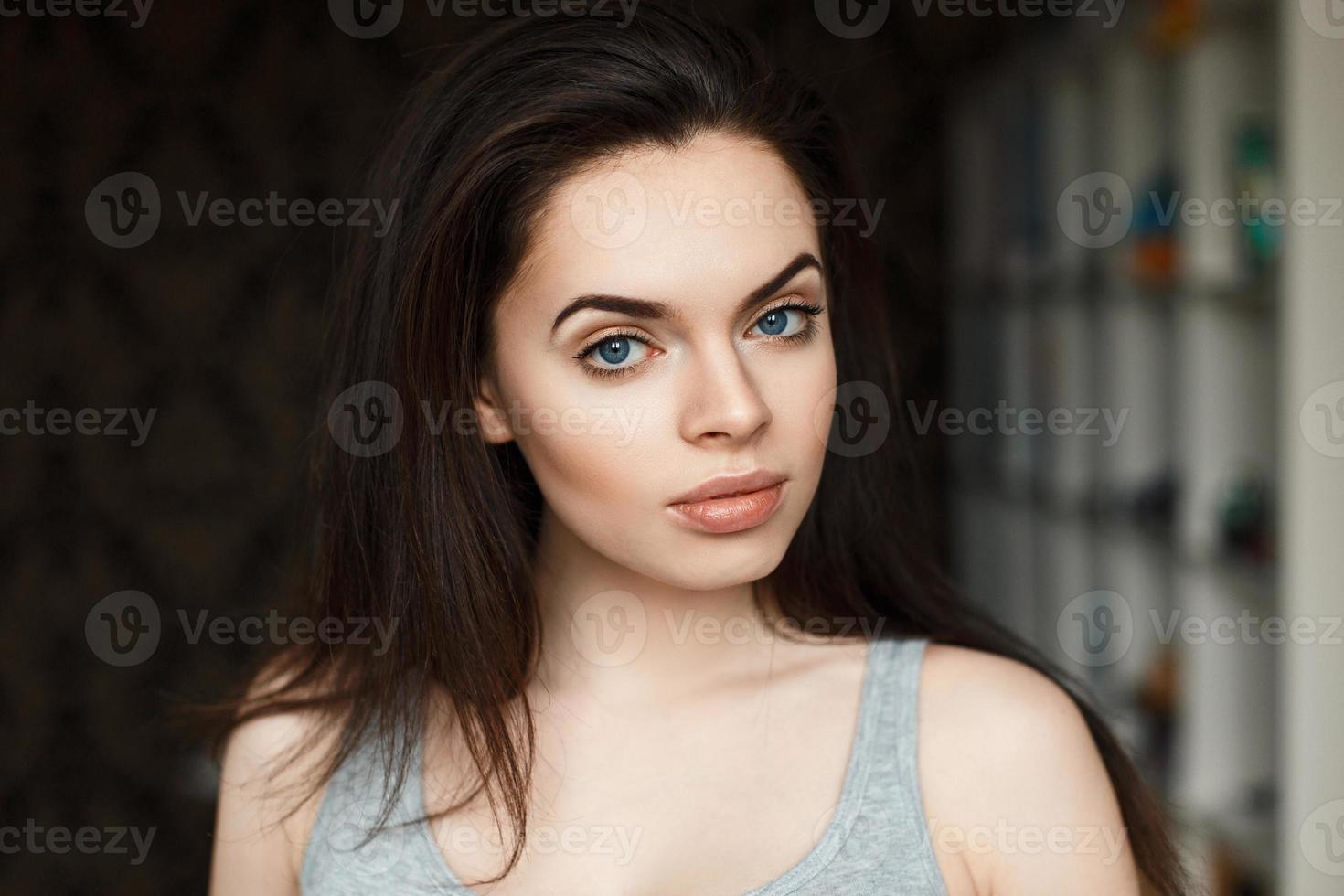 Young beautiful brunette girl in a t-shirt on the background of the room photo