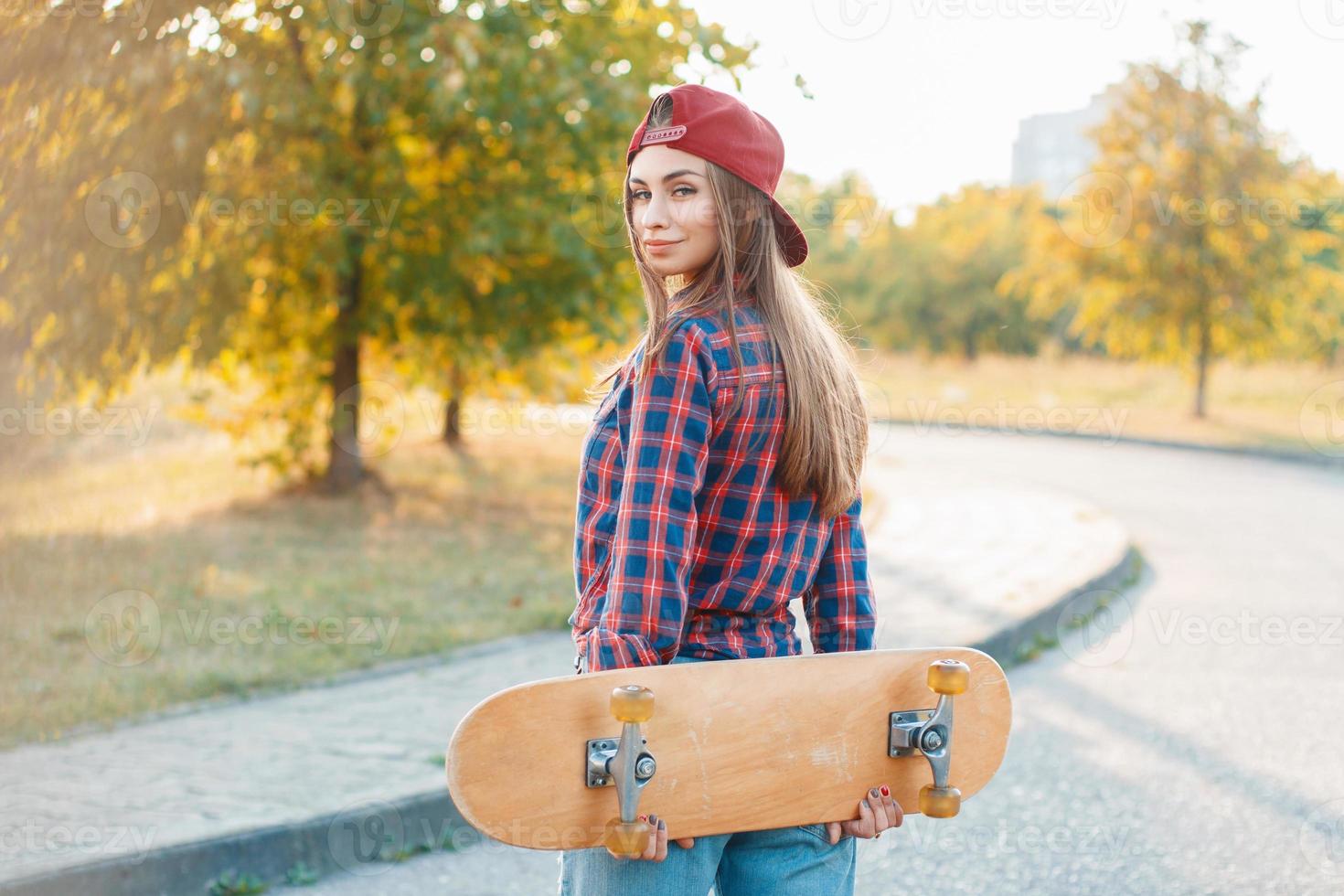Beautiful and fashion young woman posing with a skateboard photo