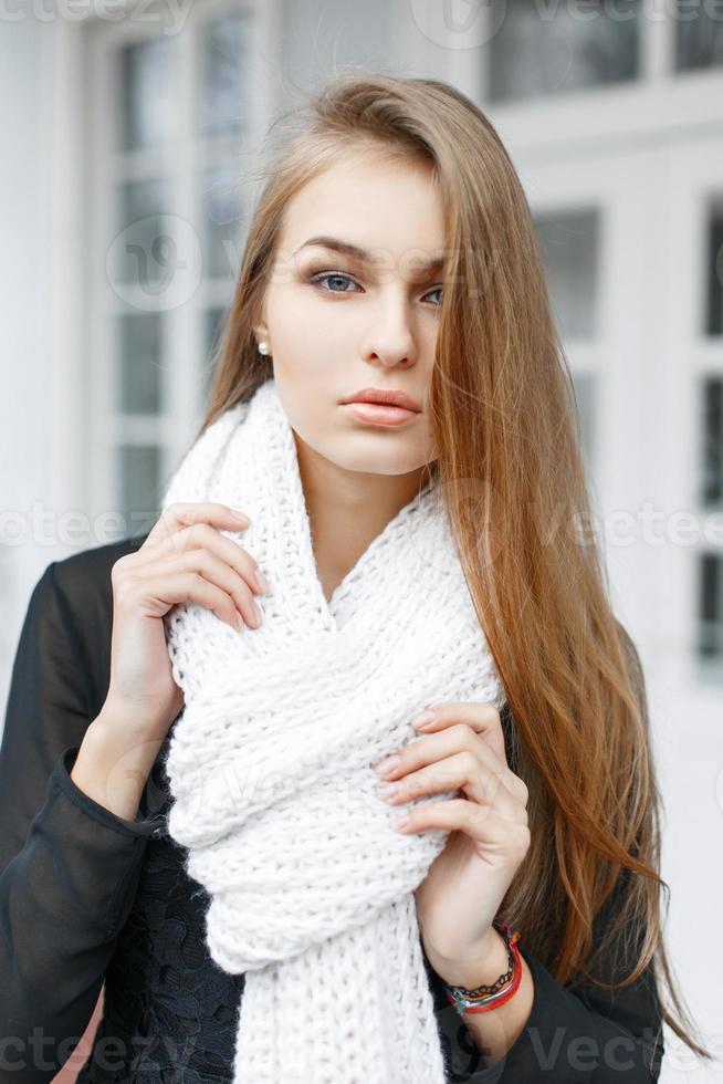 Young lovely woman with a white knitted scarf on the background of of vintage windows photo