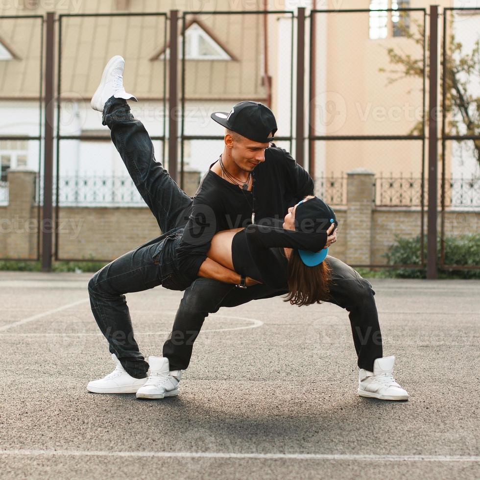 Beautiful young couple dancing hip-hop at the stadium. The guy holding the girl in his arms. photo