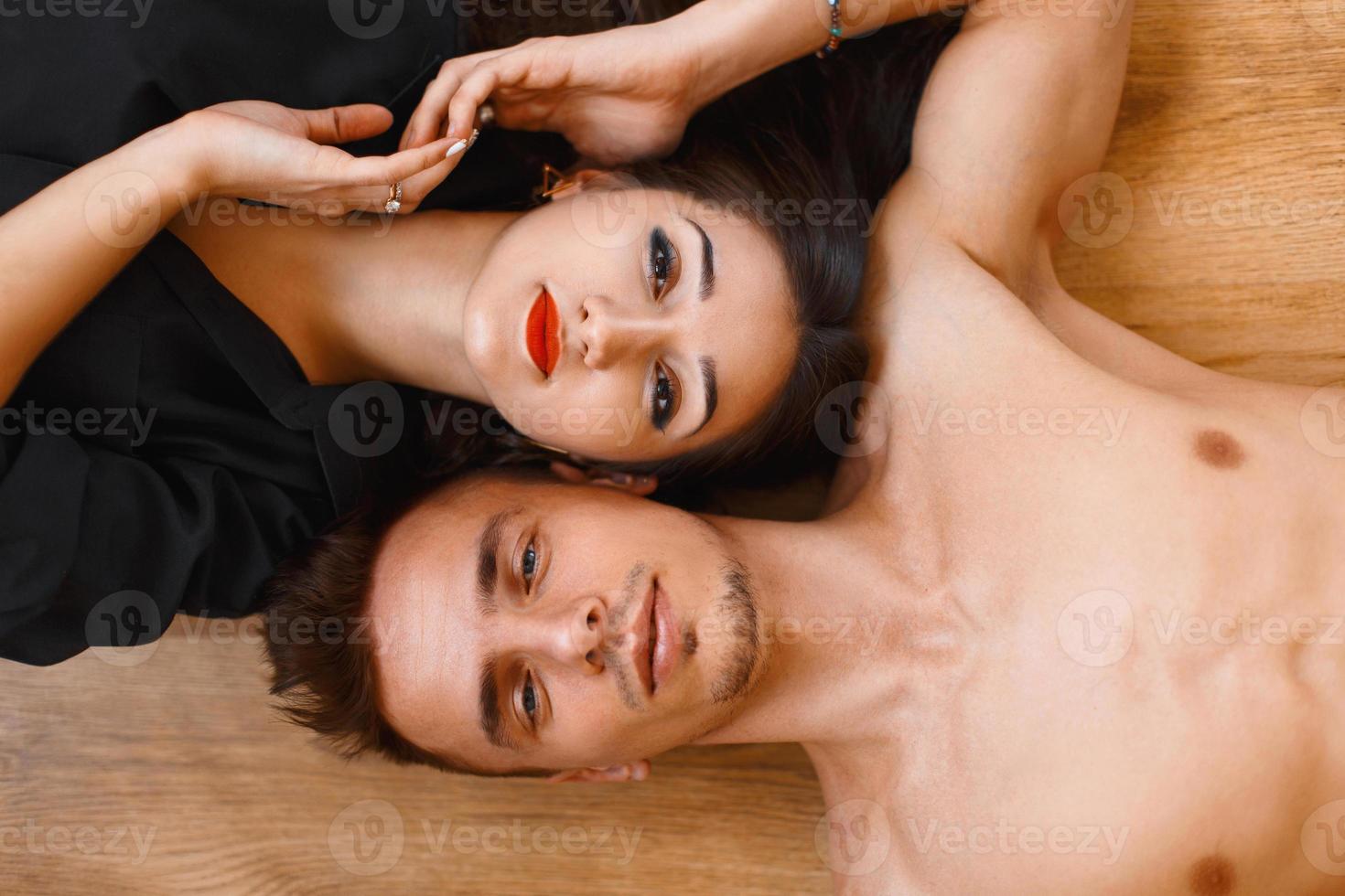 Young couple lying on the wooden floor and looking up. top view photo