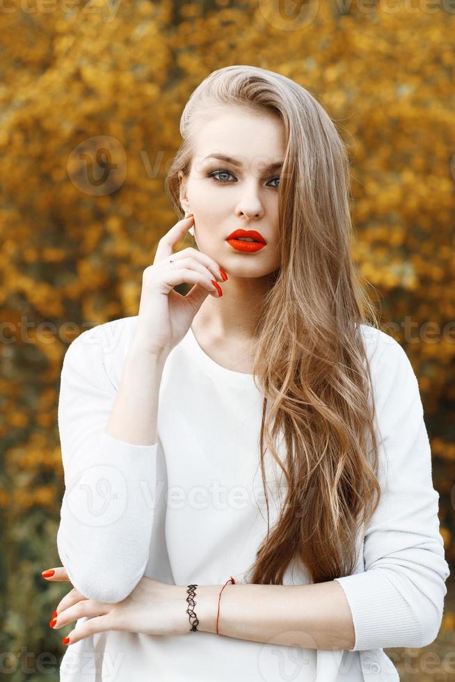 Portrait of beautiful woman with red lips on a background of yellow flowers blooming. Spring time. photo