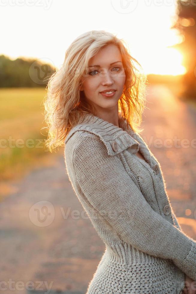 Pretty woman in knitted sweater at sunset on nature photo