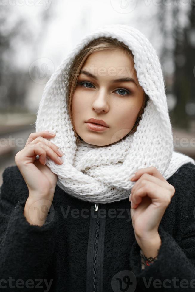 Stylish cute girl in a white knitted scarf on the background autumn park photo