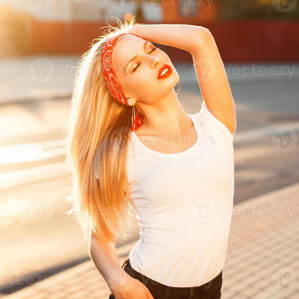bonita chica hipster con labios rojos descansando sobre un fondo de rayos al atardecer. ropa de estilo vintage. foto