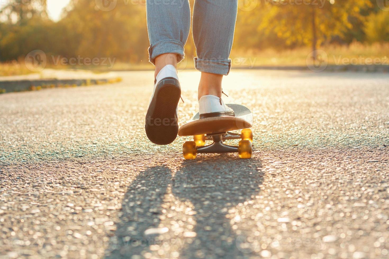 Skateboarding legs at skate park. Beautiful weather with the sunset. Woman moves forward photo