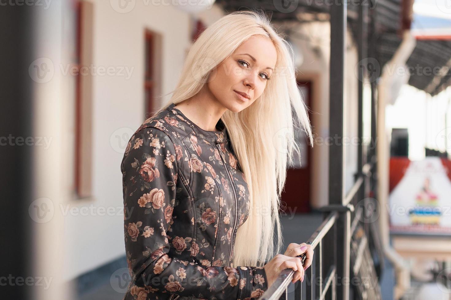 Beautiful woman in leather jacket with flowers standing near the railing. Spring. photo