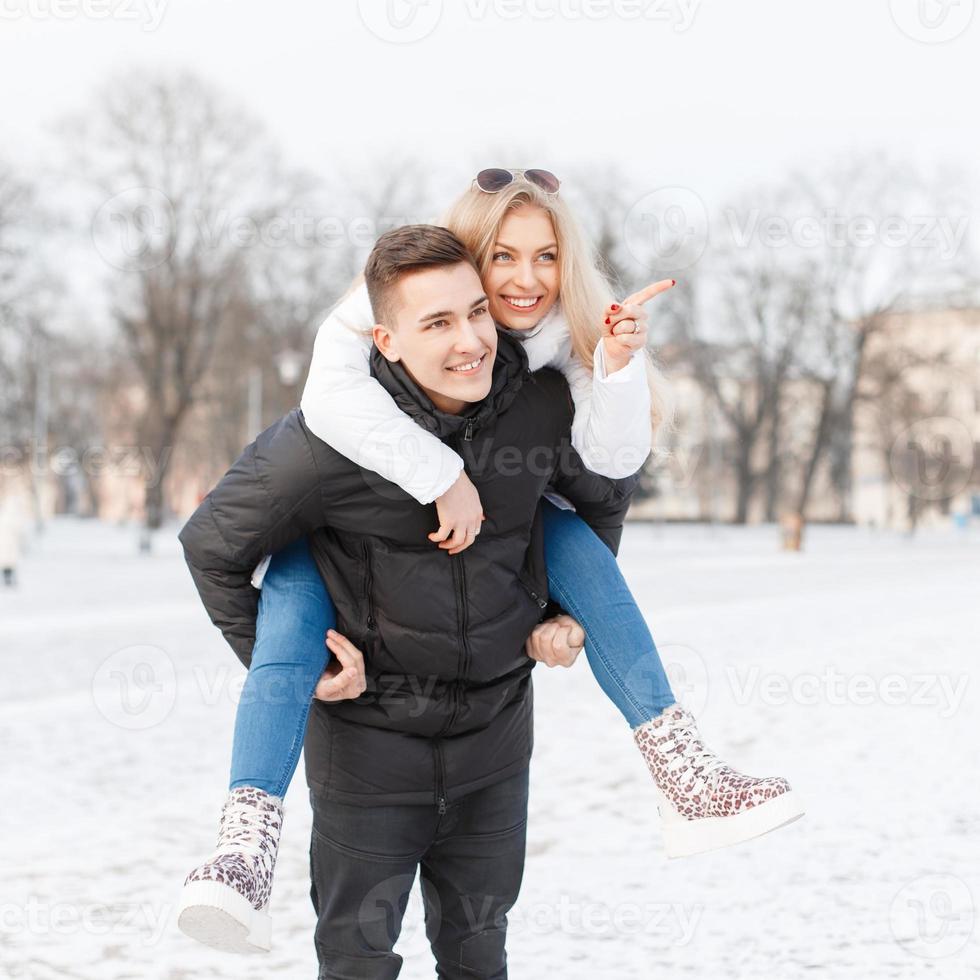 Young couple walking through the city. The guy carries the girl on the back. photo