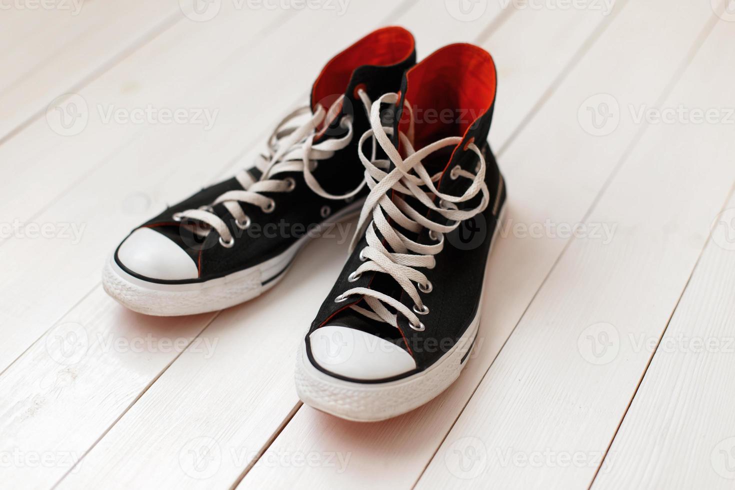 Old black sneakers with red on wooden background photo