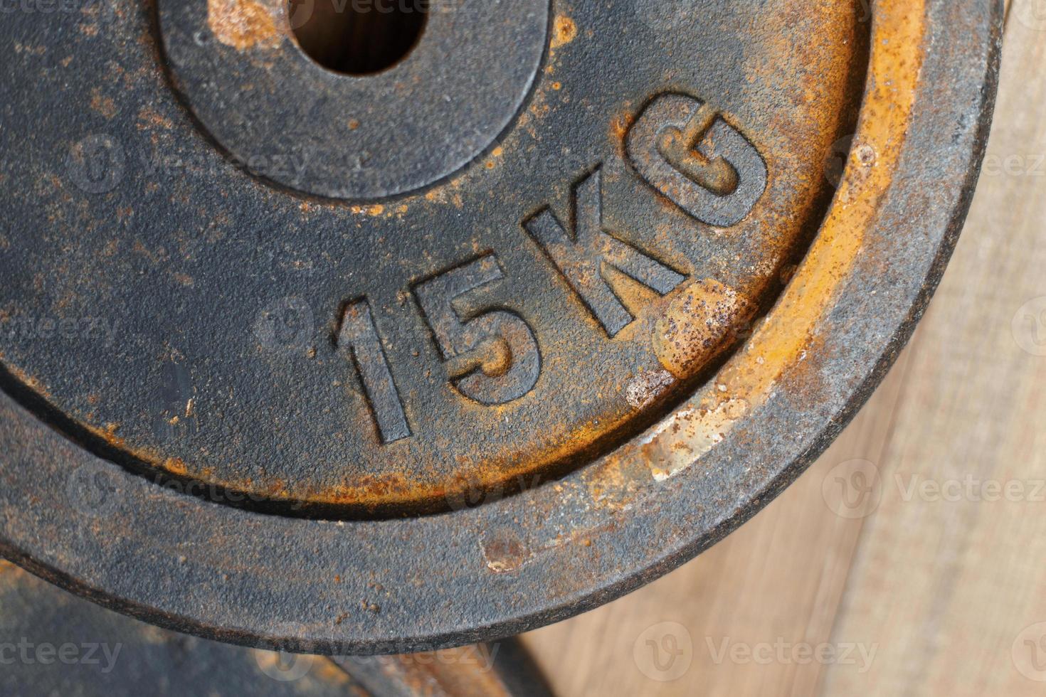 Metal weight 15 kg with rust for the bench on a wooden background photo