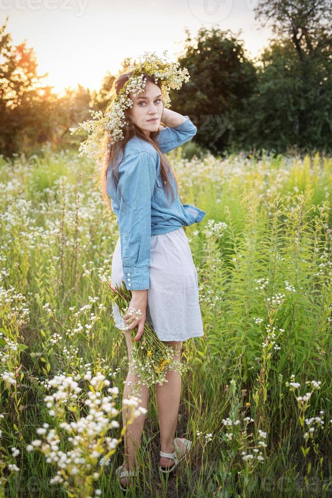 Beautiful girl  walking on field on summer with wildflowers. photo