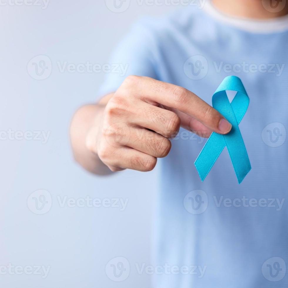 noviembre azul mes de concientización sobre el cáncer de próstata, hombre con camisa azul con la mano sosteniendo una cinta azul para apoyar la vida y la enfermedad de las personas. salud, dia internacional del hombre, padre, diabetes y dia mundial del cancer foto
