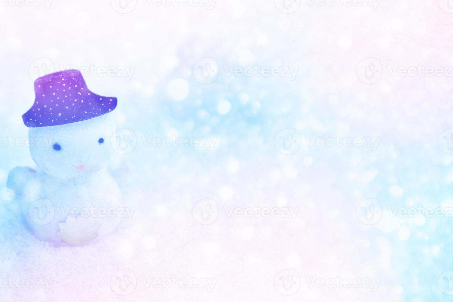 White snowman in a black hat in the snow. photo