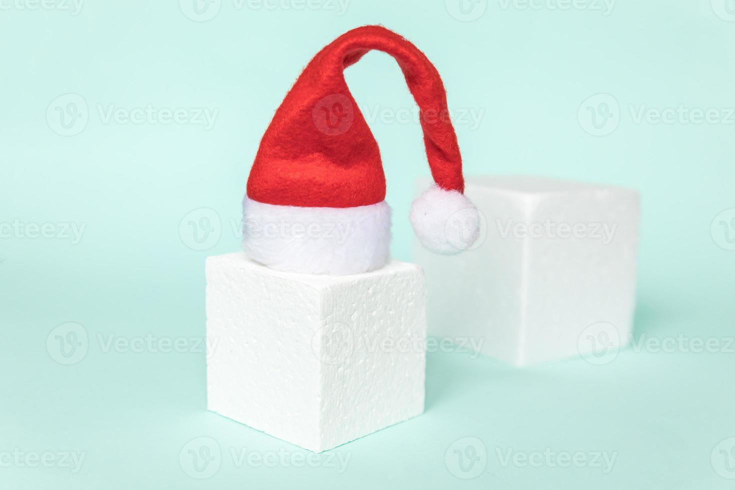 Simply minimal composition winter object Santa hat and cube shapes geometric form podium isolated blue pastel background. Christmas New Year december time for celebration concept. Mockup, copy space photo