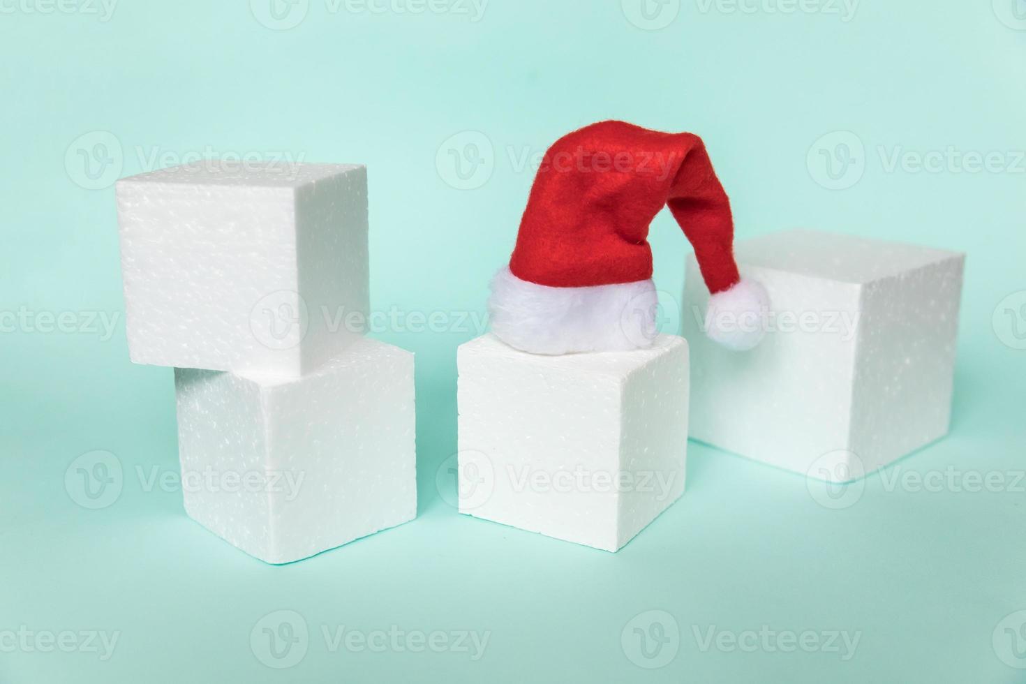 Simply minimal composition winter object Santa hat and cube shapes geometric form podium isolated blue pastel background. Christmas New Year december time for celebration concept. Mockup, copy space photo