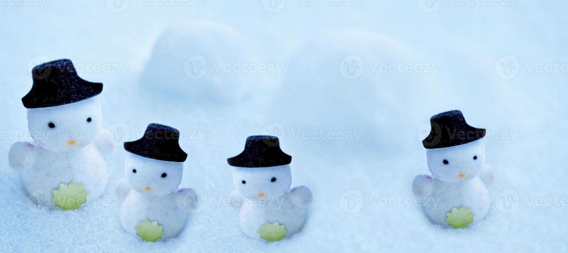 White snowman in a black hat in the snow. photo