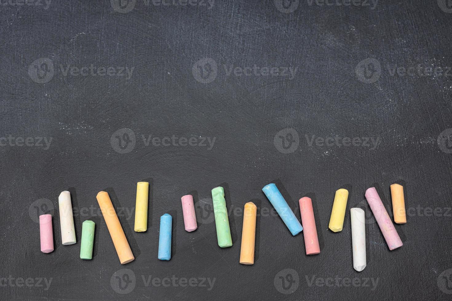 Variation of colored chalk sticks on blackboard. Copy space. Back to school photo