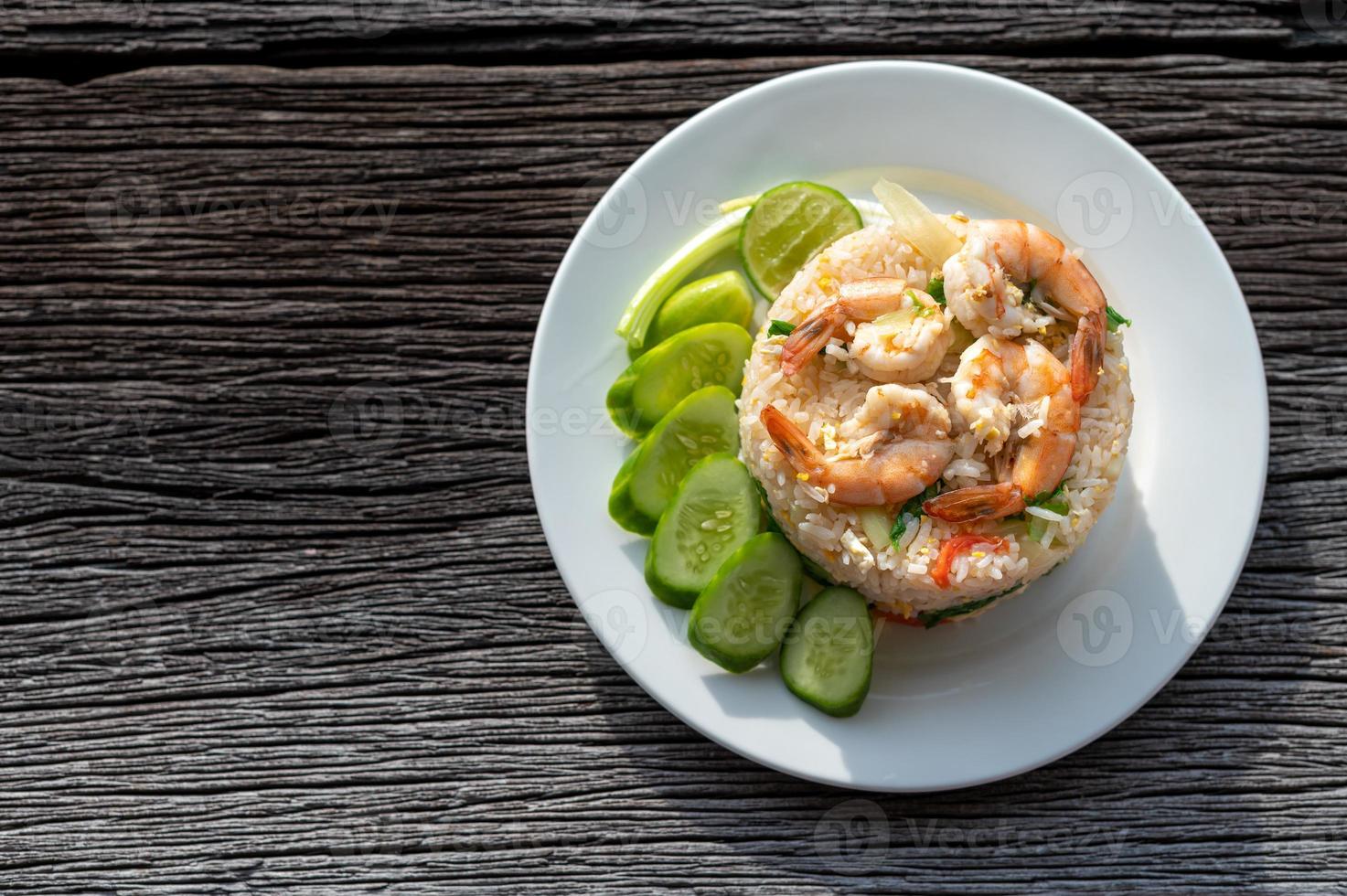 Thai fried rice with prawns and vegetables on wooden table photo