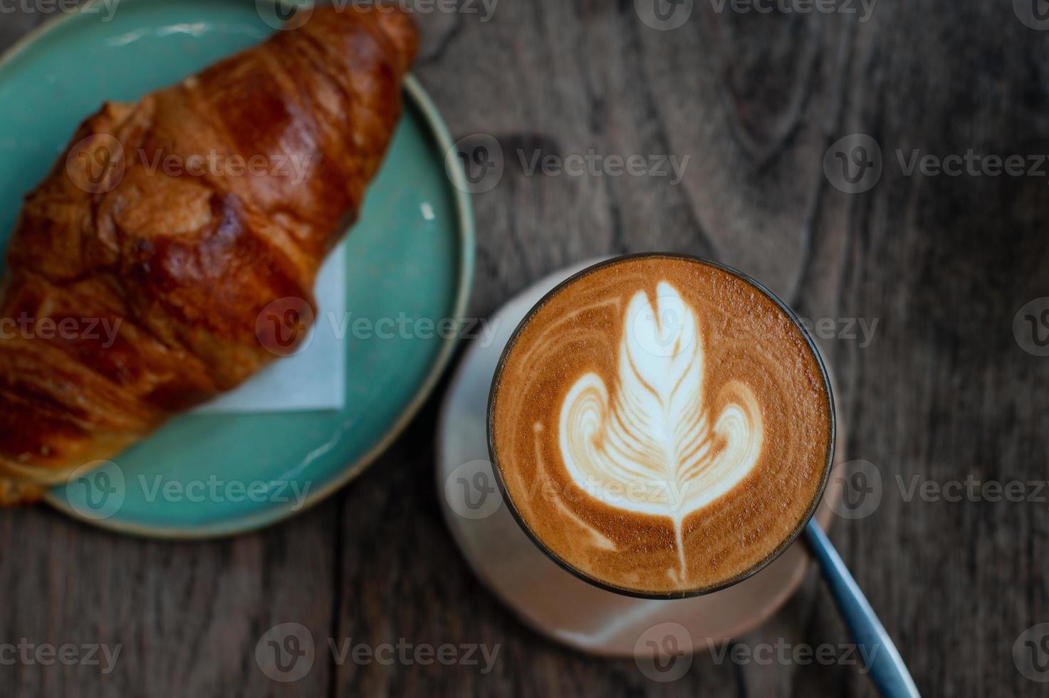 Latte art and croissant  on rustic wooden table photo