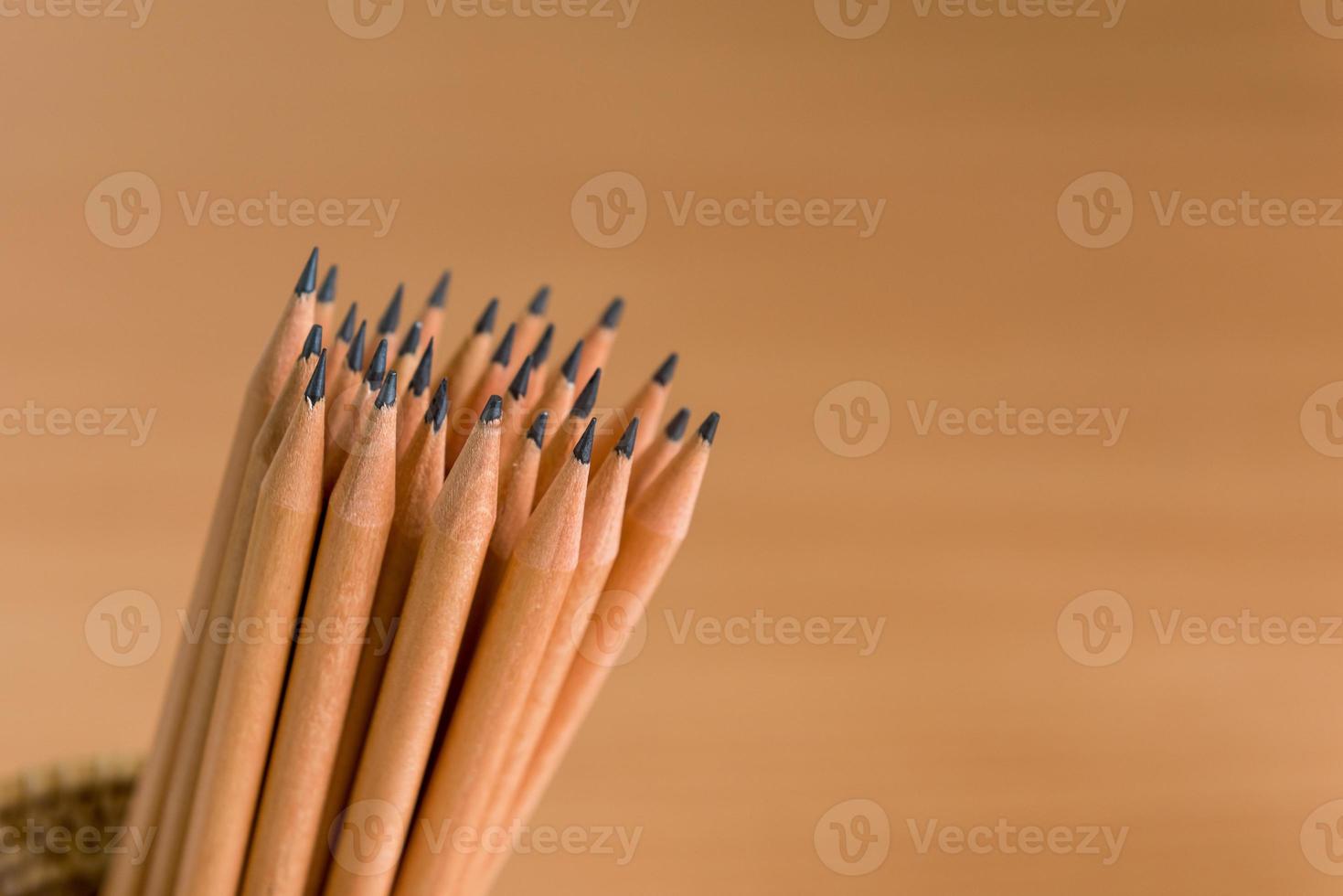 Group of pencils standing on brown background photo