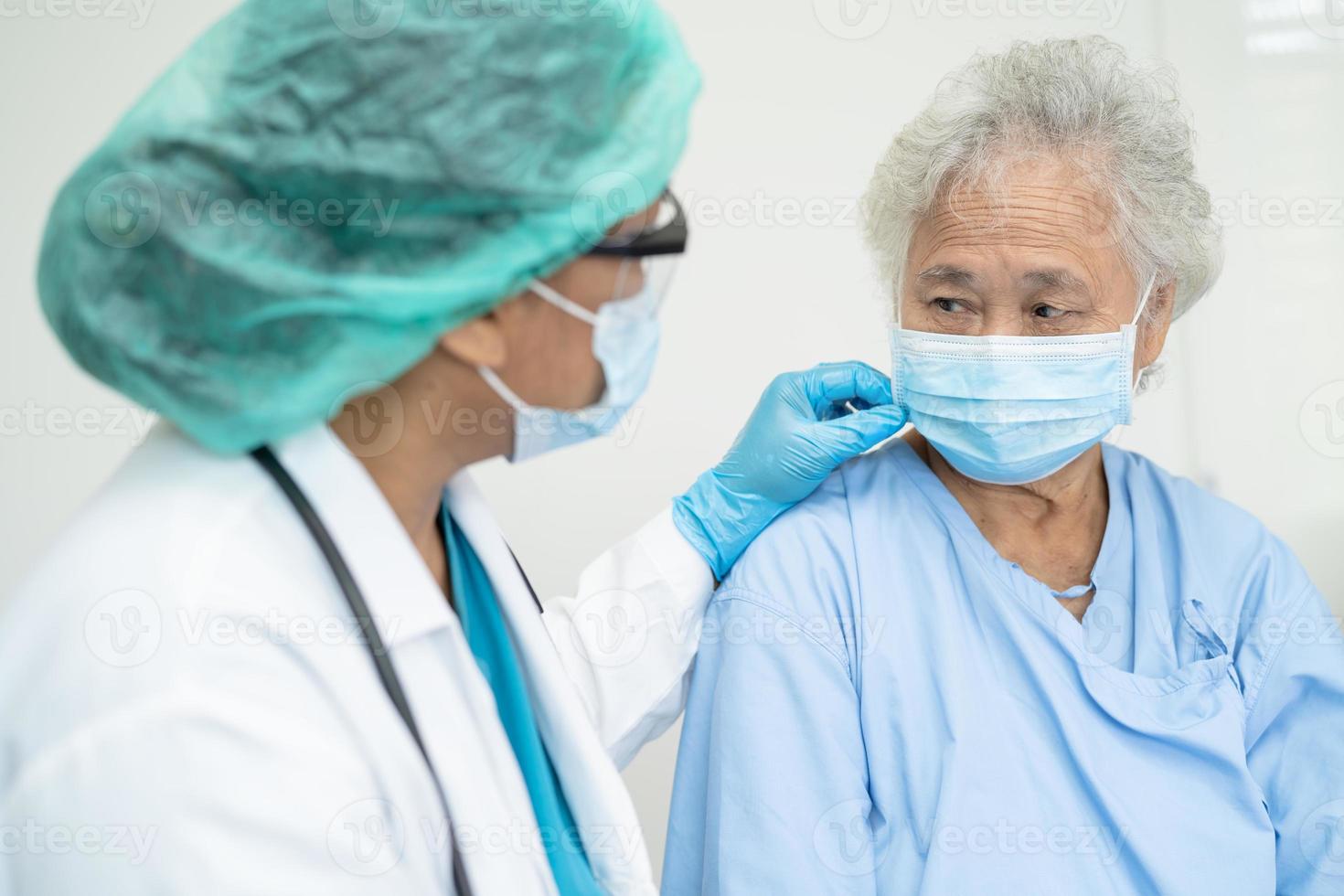 Doctor help Asian senior or elderly old lady woman patient wearing a face mask in hospital for protect safety infection and kill Covid-19 Coronavirus. photo