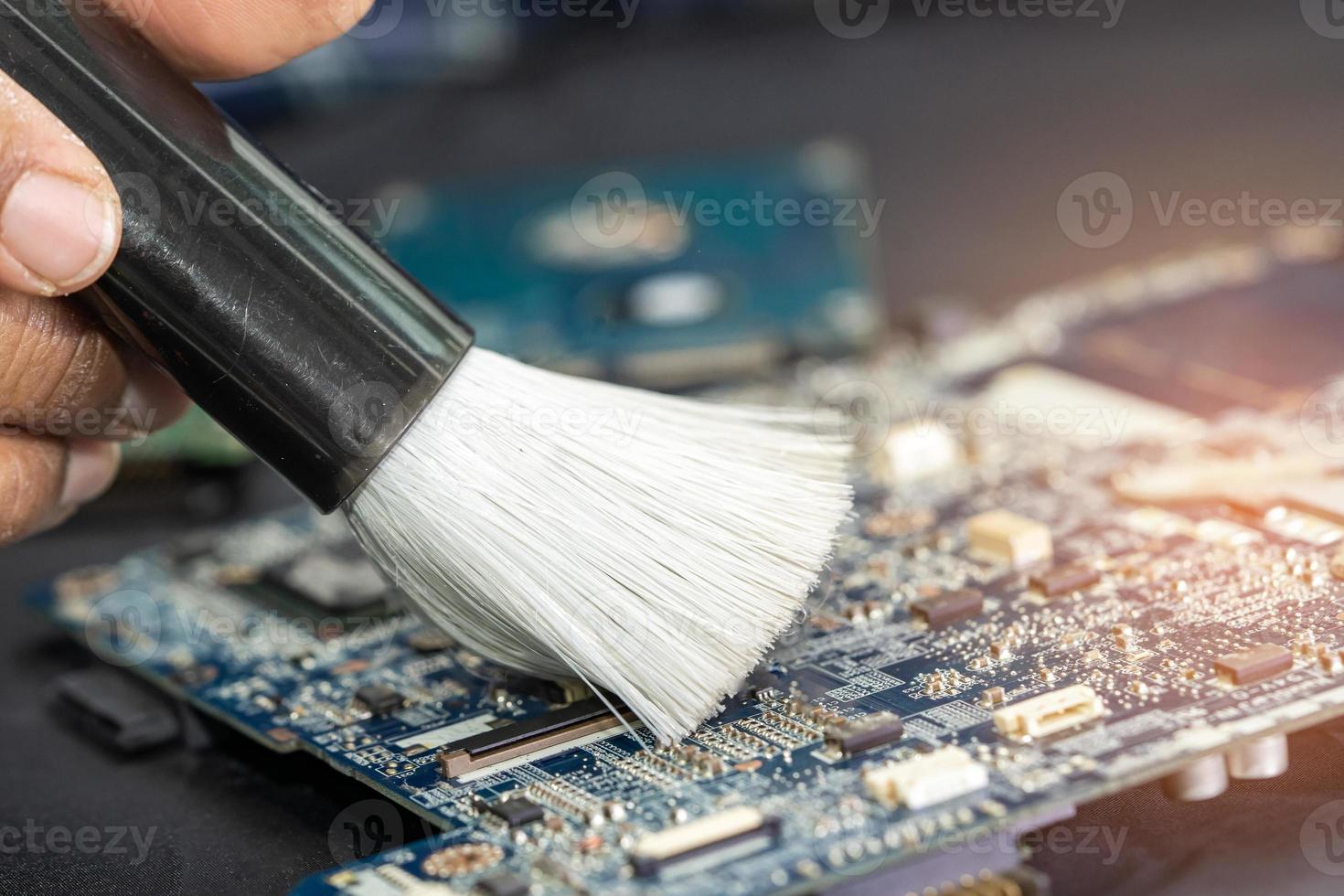 Technician use brush and air blower ball to clean dust in circuit board computer. Repair upgrade and maintenance technology. photo