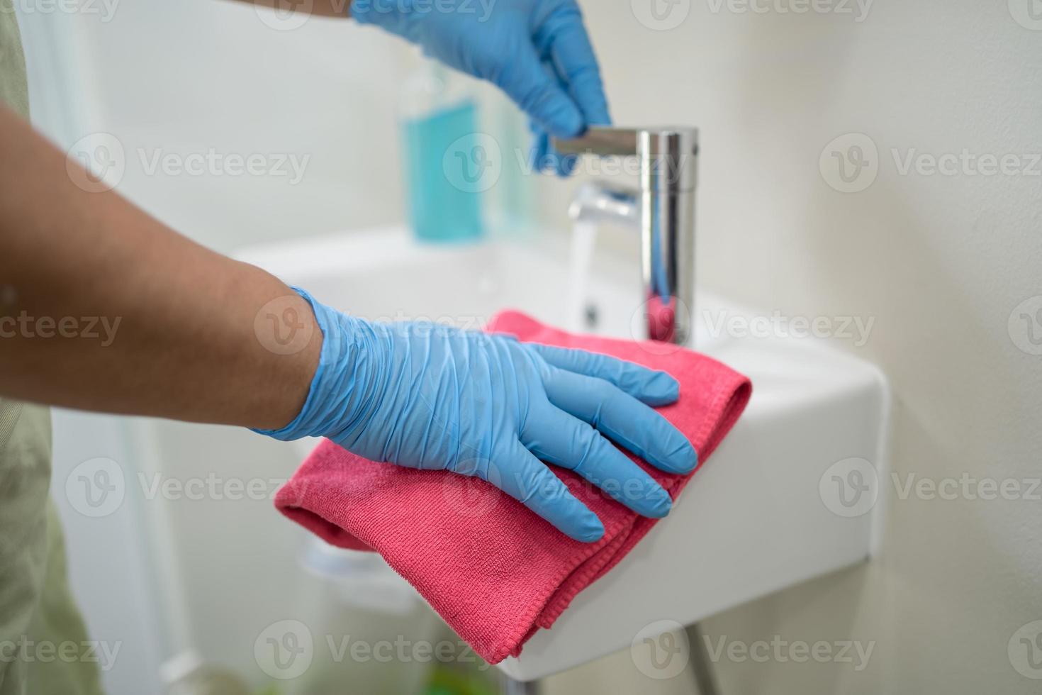 Maid cleaning wash and scrub basin in toilet at home. photo