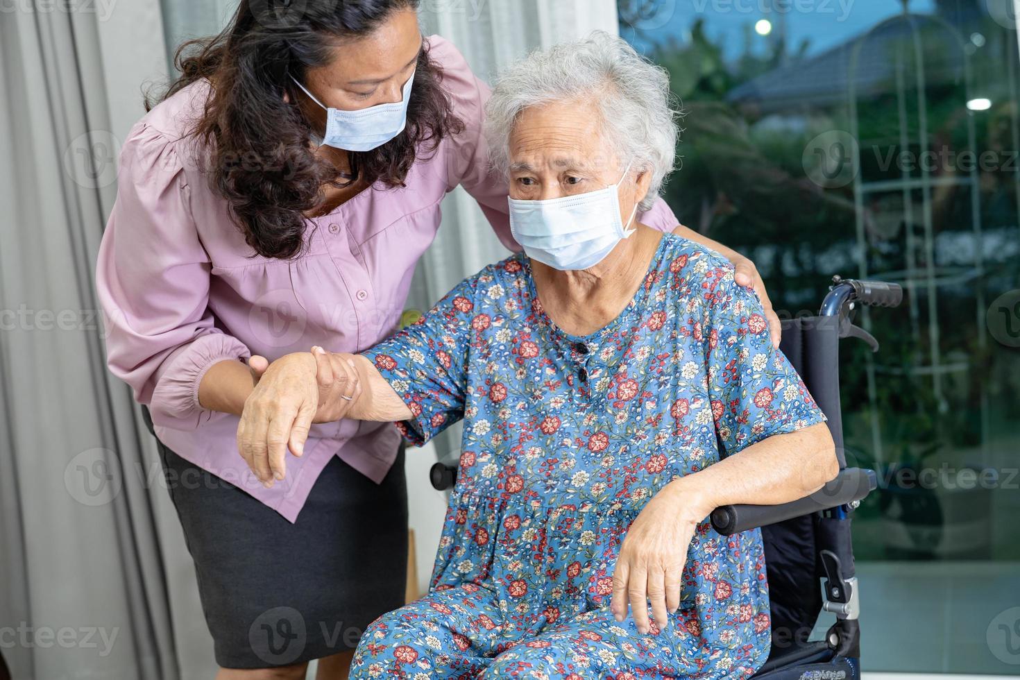 el cuidador ayuda a una anciana asiática o anciana sentada en silla de ruedas y usando una máscara facial para proteger la infección de seguridad covid 19 coronavirus. foto