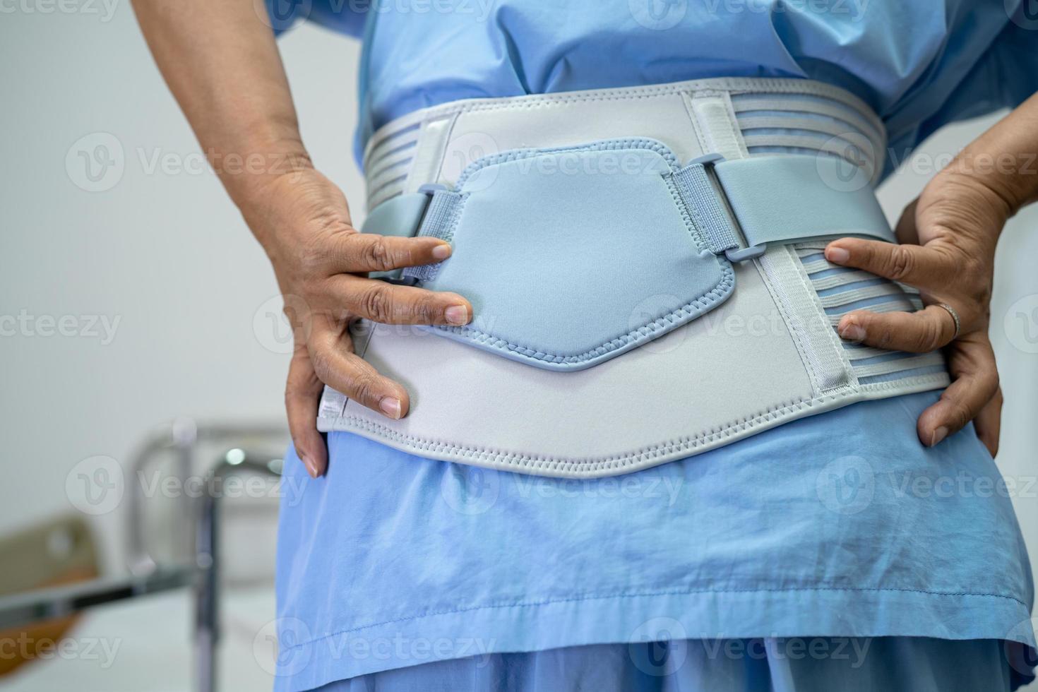 Asian lady patient wearing back pain support belt for orthopedic lumbar with walker. photo