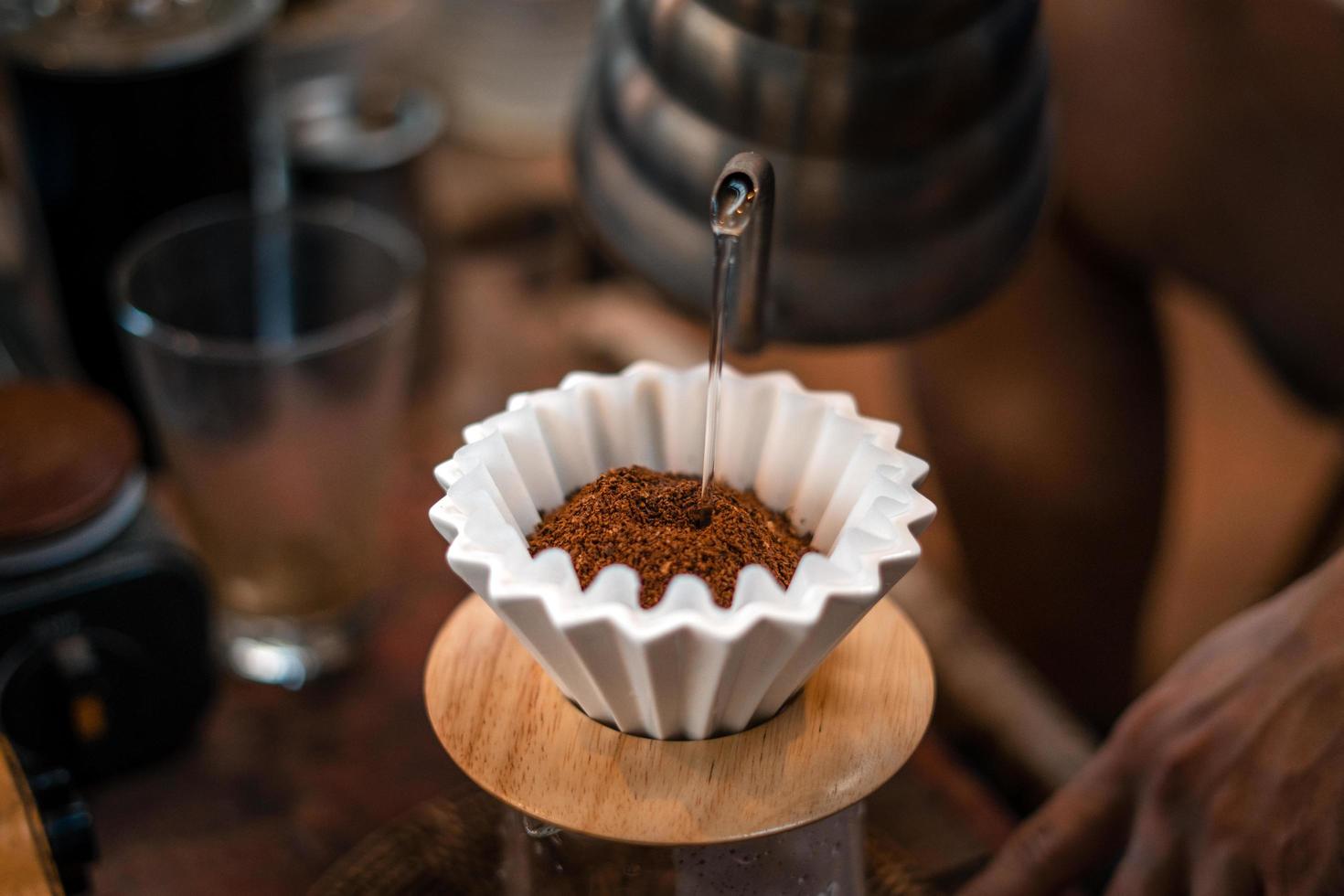 Drip coffee, barista pouring water on coffee ground with filter photo