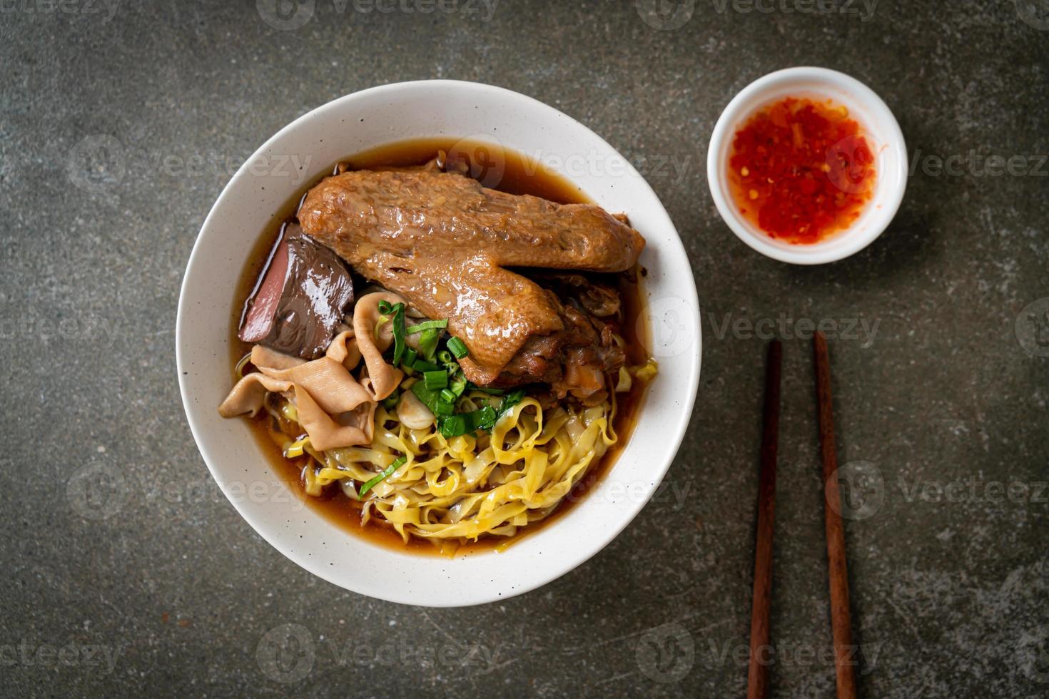 egg noodles with stewed and braised duck in brown soup photo