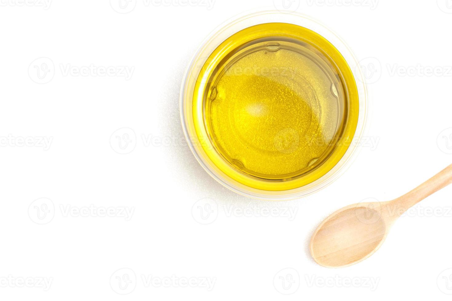 Yellow vegetable oil in a transparent bowl with a wooden spoon on a white background.top view,top-down,flat lay. photo