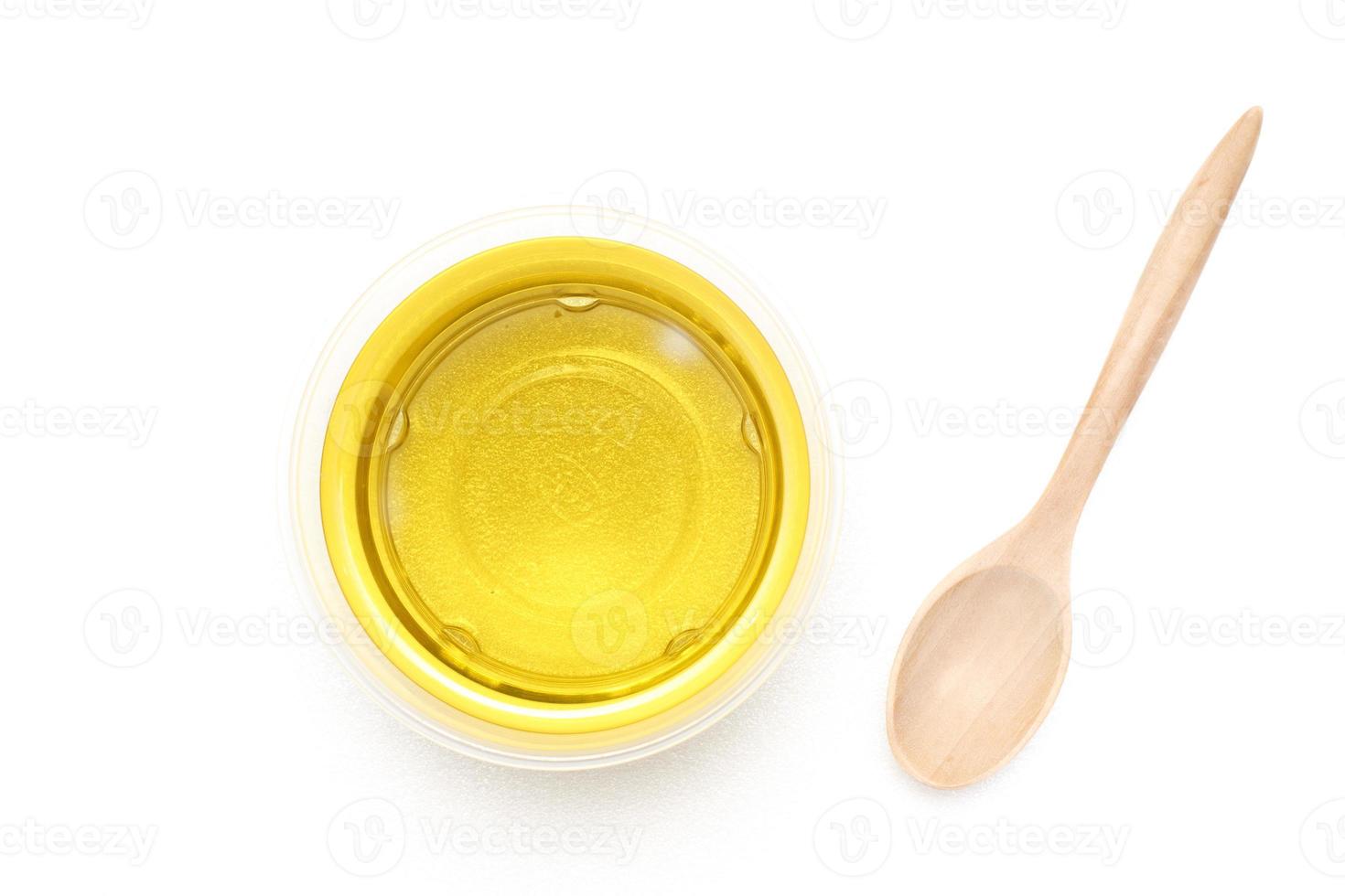 Yellow vegetable oil in a transparent bowl with a wooden spoon on a white background.top view,top-down,flat lay. photo