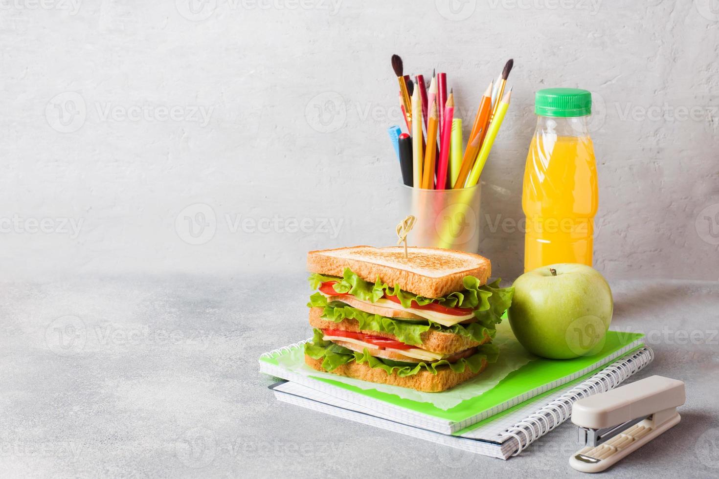 Healthy lunch for school with sandwich, fresh apple and orange juice. Assorted colorful school supplies. Copy space. photo