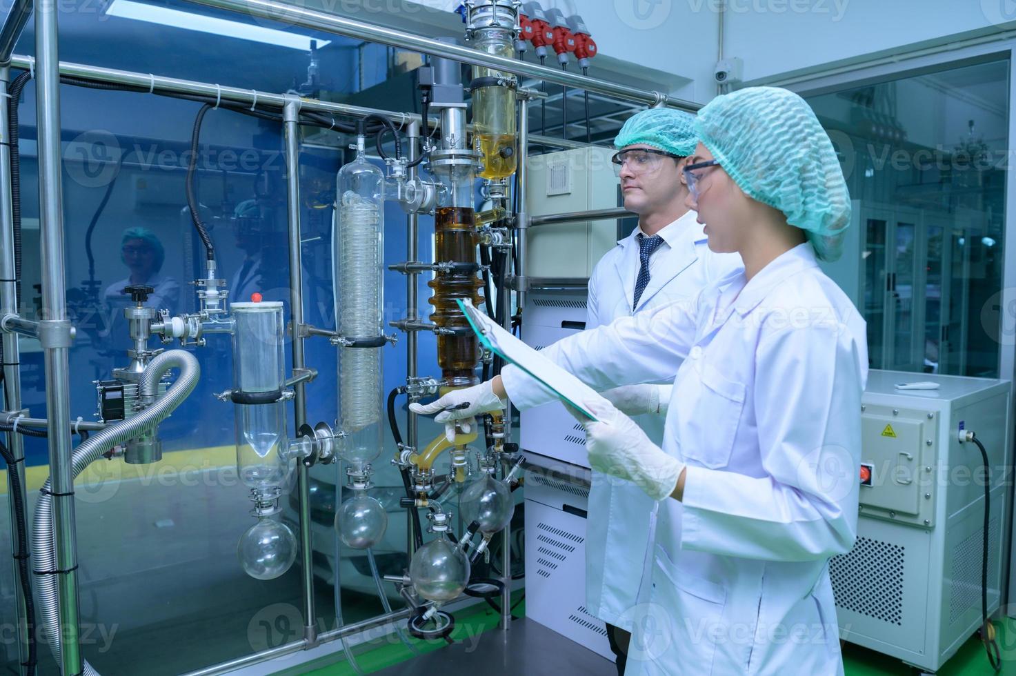 Scientists and assistants are in the machine room extracting oil and cannabis seeds. Inspecting cannabis oil extractor before starting to extract the prepared cannabis photo