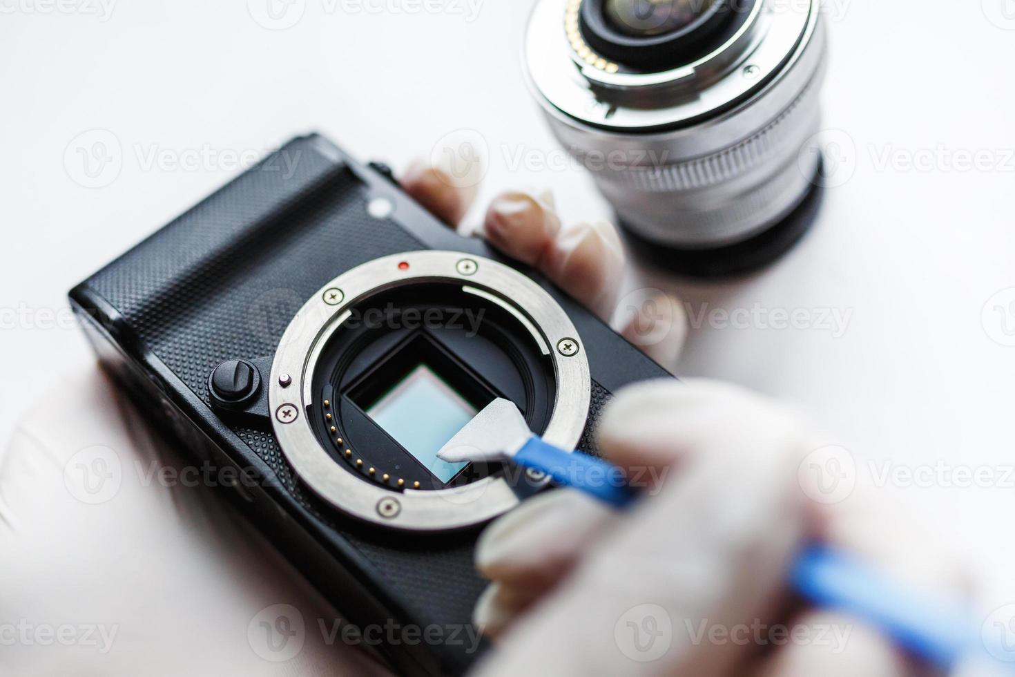 Close-up of mirrorless digital APS-C dirty camera matrix sensor cleaning and maintenance with swab, photographer cleaning photocamera on white background photo