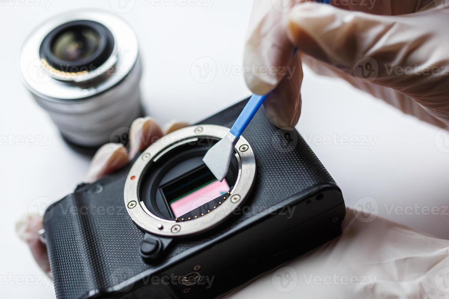 Close-up of mirrorless digital APS-C dirty camera matrix sensor cleaning and maintenance with swab, photographer cleaning photocamera on white background photo