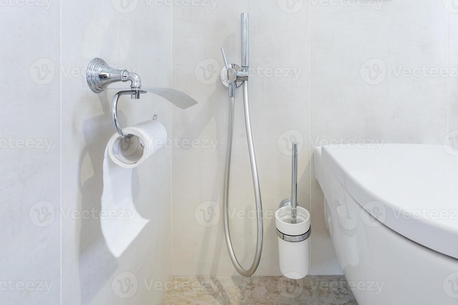 toilet and detail of a corner shower bidet with toilet paper holder on wall mount shower attachment photo