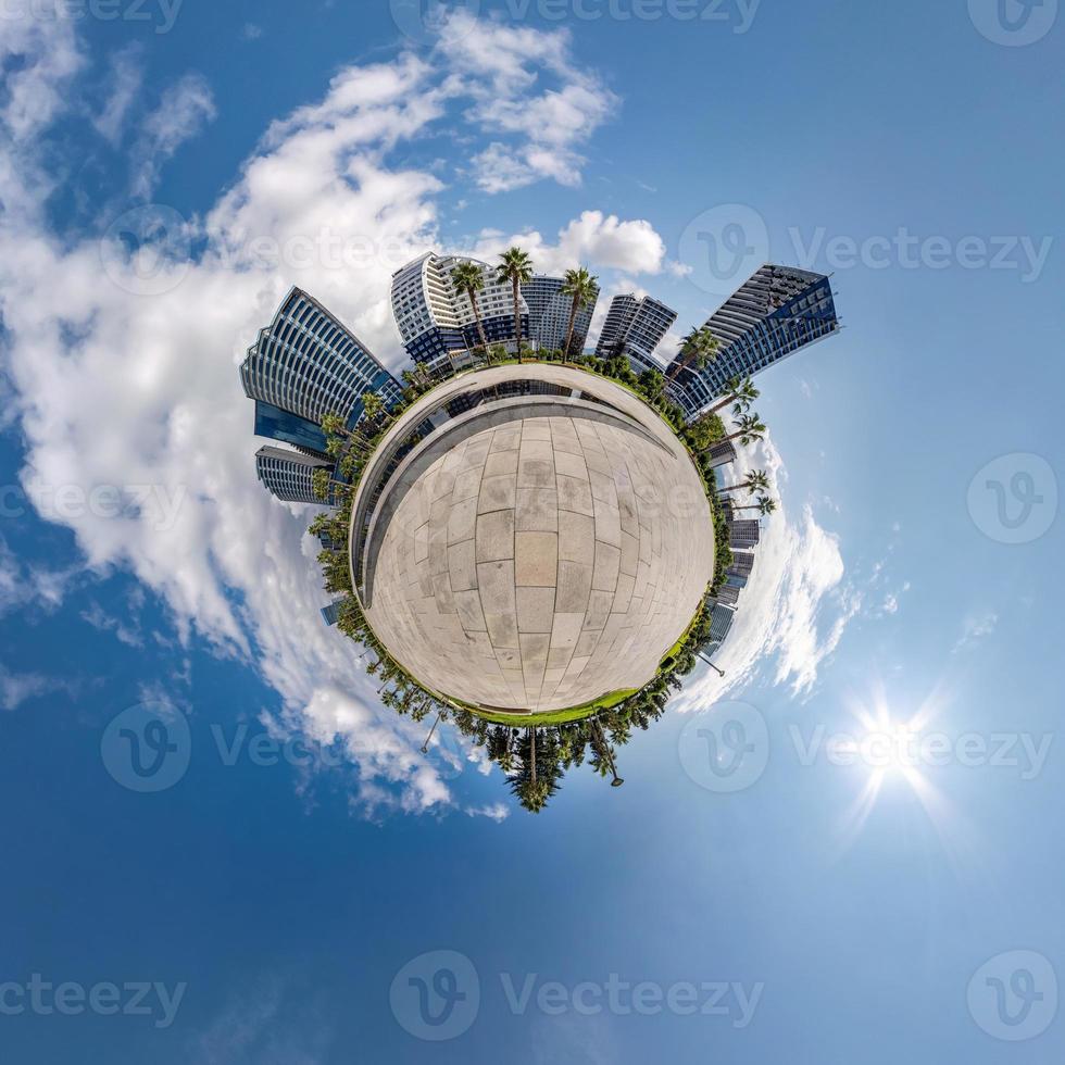 tiny planet in blue sky with clouds in city center near modern skyscrapers or office buildings. Transformation of spherical 360 panorama in abstract aerial view. photo